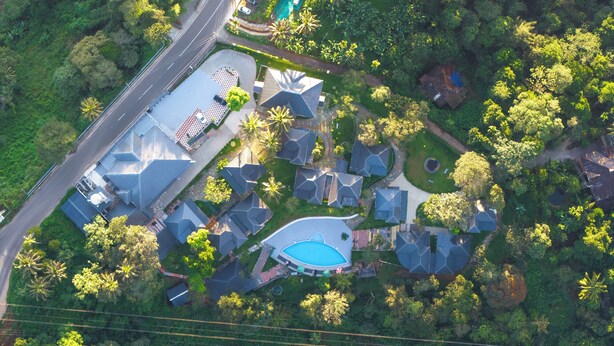 Vue aérienne d’un quartier résidentiel avec plusieurs maisons, une piscine et une route.