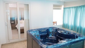 Une salle de bain moderne dotée d’une grande baignoire, d’une porte coulissante en verre donnant sur une chambre, et offrant une vue sur un balcon.