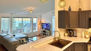 A modern kitchen with a large island, dark cabinets, and pendant lighting.