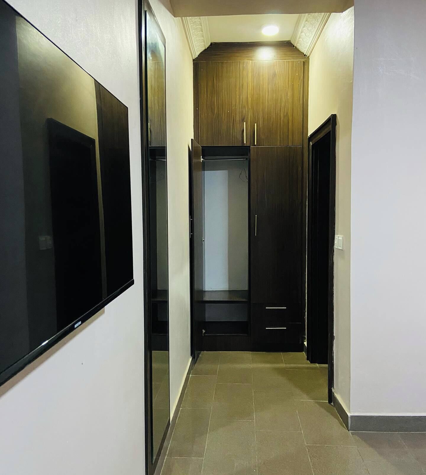 A hallway with a wooden wardrobe and a mirrored wardrobe.
