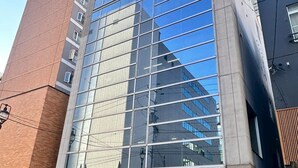 A modern building with a glass facade, a brick section on the left, and a sign reading "TAKETO BLOG" at the entrance. - Fierement inn (Sapporo)