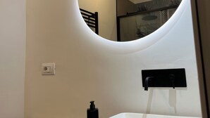 A bathroom with a round mirror, a white sink, and a wooden countertop. - Turin Central Suite (Turin)