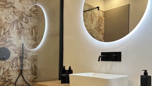 A modern bathroom with a large mirror, a white sink, and a shower with a glass door. - Turin Central Suite (Turin)