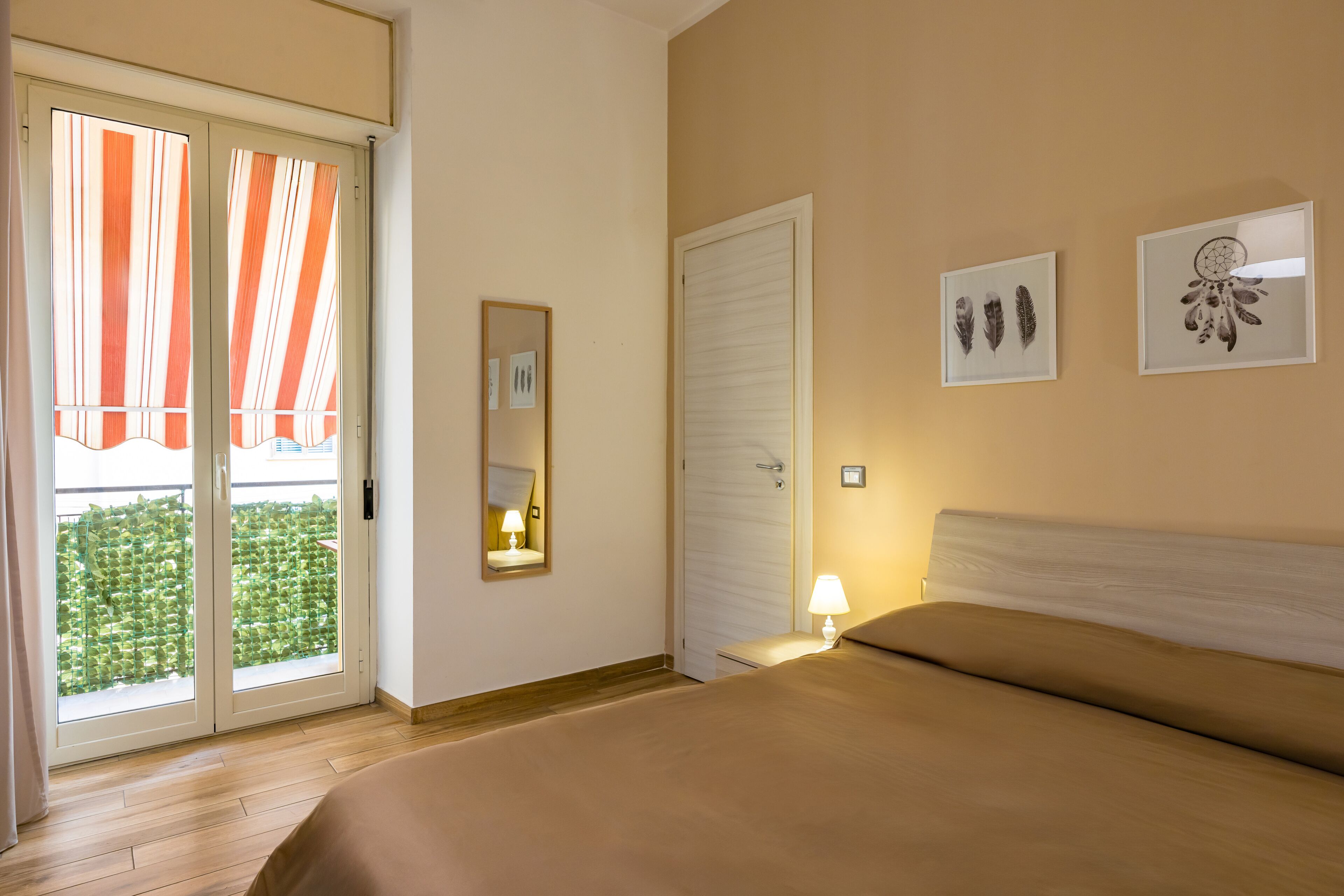 Ein Hotelzimmer mit Bett, Tür, Spiegel und Fenster mit Blick auf Grünflächen.