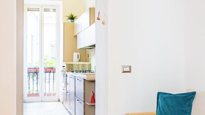 A modern apartment with a kitchen, a living area with a sofa and a blue pillow, and a wooden floor. - Cozy Escape by Napoliapartments (Naples)