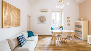 A modern living room with a sofa, a dining table, and a kitchen area. - Cozy Escape by Napoliapartments (Naples)