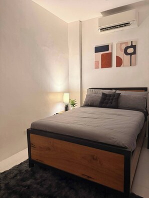 A bedroom with a bed, a nightstand, a lamp, and abstract wall art.