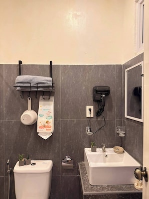 A bathroom with a toilet, sink, and a towel rack with a towel.