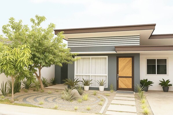 A modern house with a minimalist design, featuring a large window, a wooden door, and a well-maintained garden with various plants and a gravel pathway.