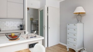 Et moderne badeværelse med en hvid kommode, et hvidt skab og en hvid stol.