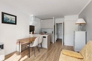 Une cuisine moderne avec des meubles blancs, une table à manger en bois et un petit îlot central.