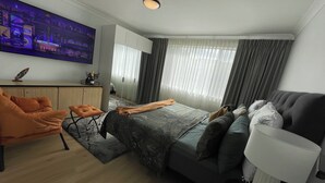 Ein modernes Hotelzimmer mit Bett, Sofa, Schreibtisch und Fernseher.