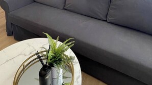 Ein modernes Wohnzimmer mit grauem Sofa, einem Marmortisch und einer Topfpflanze.