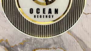Un panneau circulaire sur lequel on peut lire le texte « OCEAN REGENCY », le tout sur un fond en marbre.