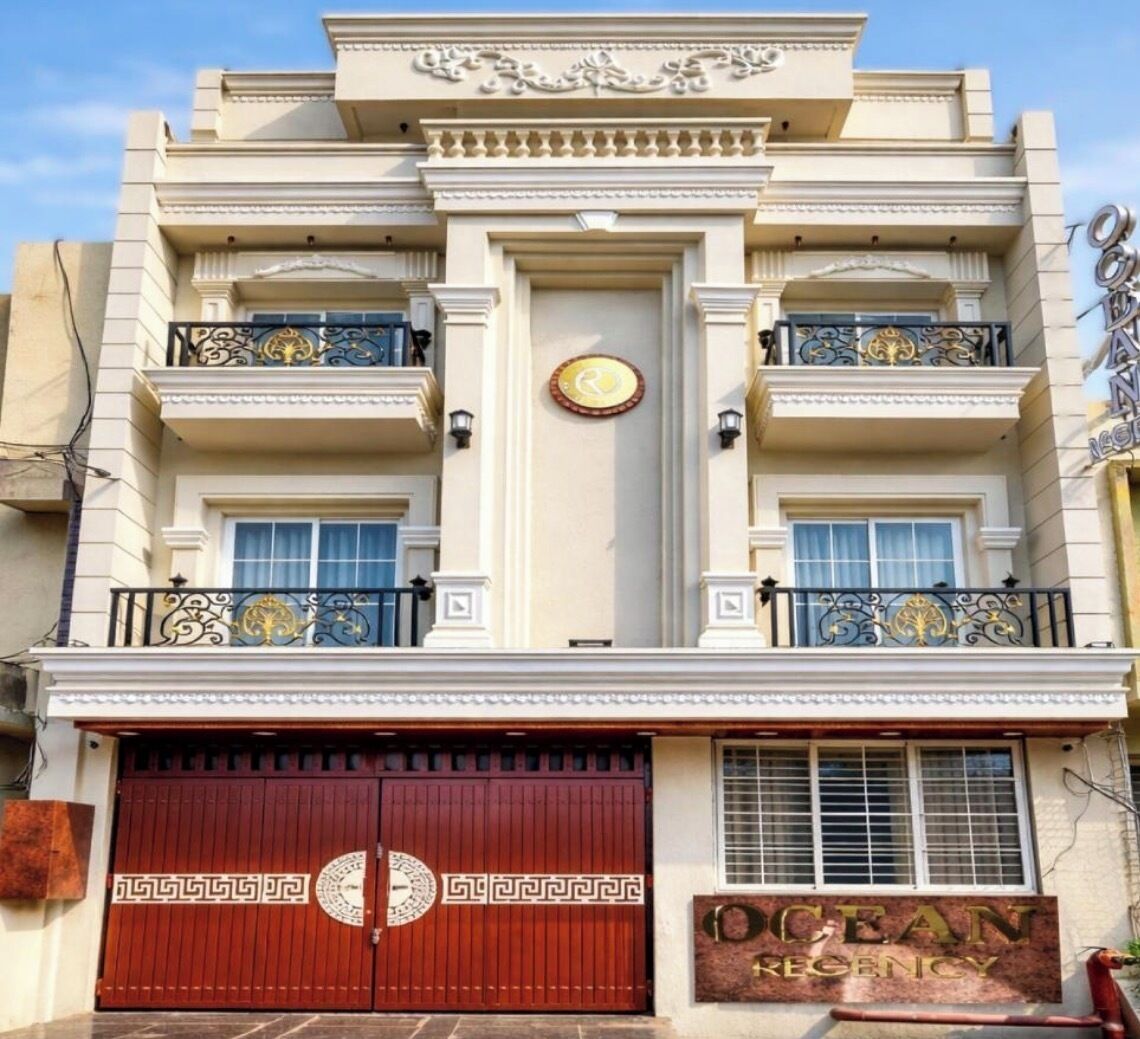 A building with a large, ornate entrance gate, a prominent sign reading "OCEAN REGENCY," and a symmetrical facade with decorative railings and a clock.