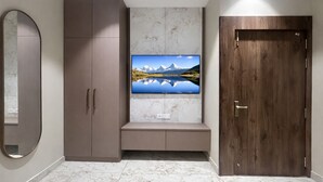 Une pièce dotée d’une grande armoire, d’un téléviseur fixé au mur qui diffuse des images d’un paysage pittoresque, et d’une porte en bois.