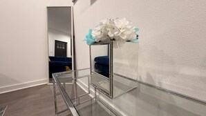 Una mesa de vidrio con un espejo y un arreglo floral blanco.