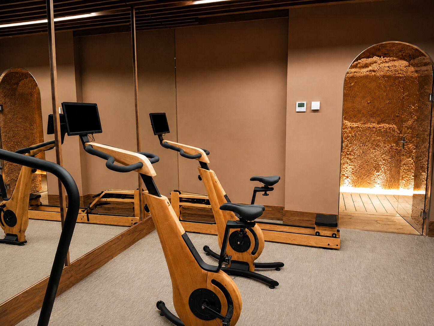 Un gimnasio con bicicletas estáticas, un espejo grande y una pared de madera.