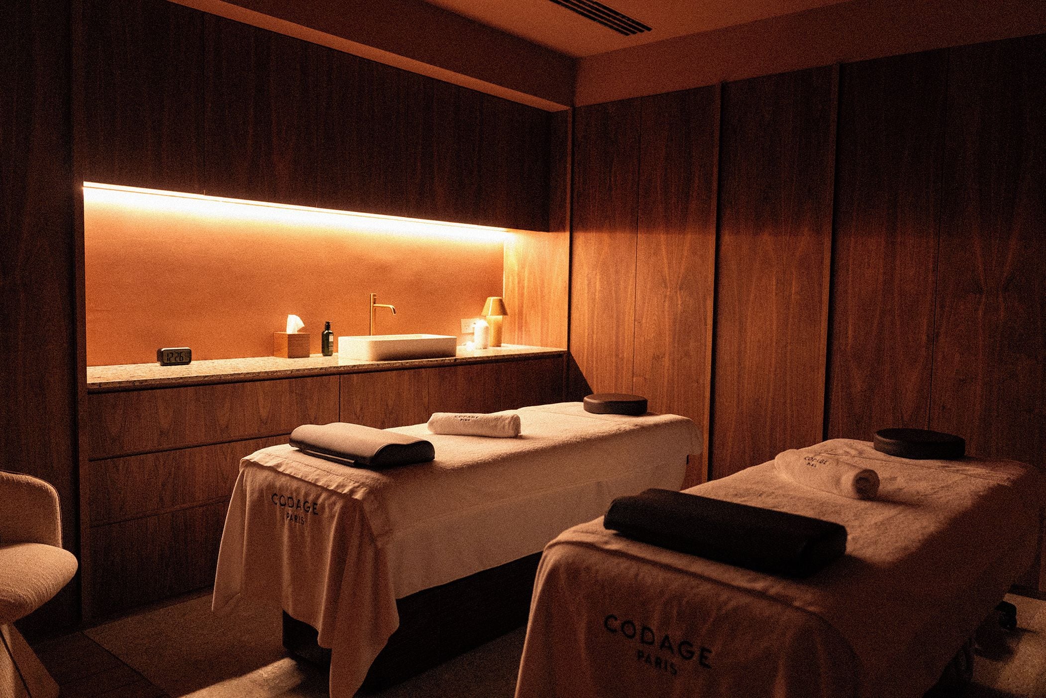 Une salle de spa équipée d’une table de massage, d’un petit lavabo et d’un miroir.