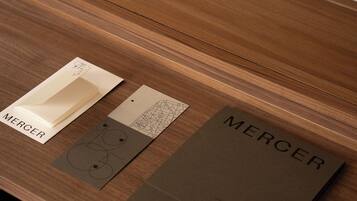 Ein Holztisch mit einer braunen Ordner, beschriftet 'MERCER', und zwei Karten mit Designs.