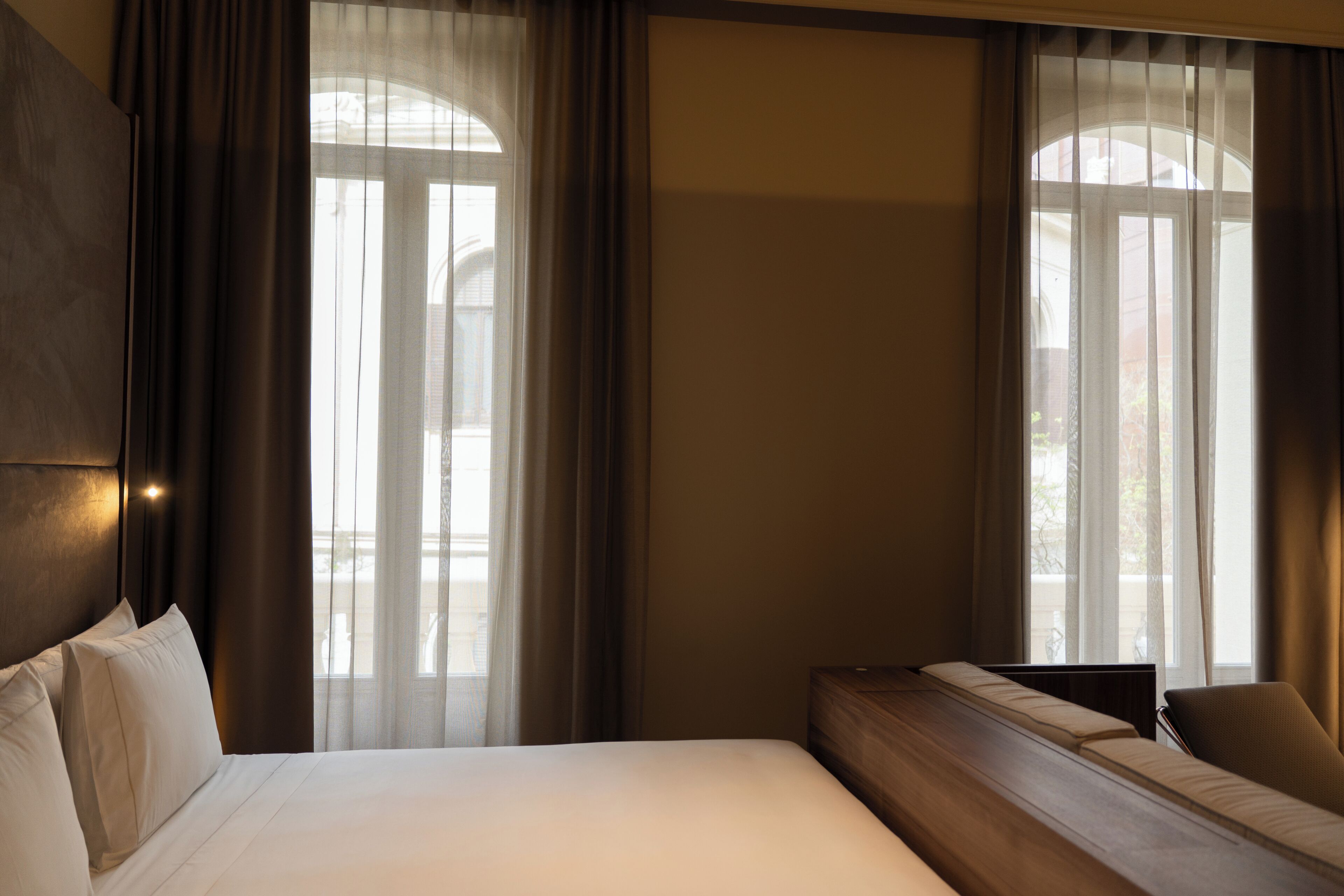 Una habitación de hotel con una cama grande, un sofá y una ventana con cortinas.