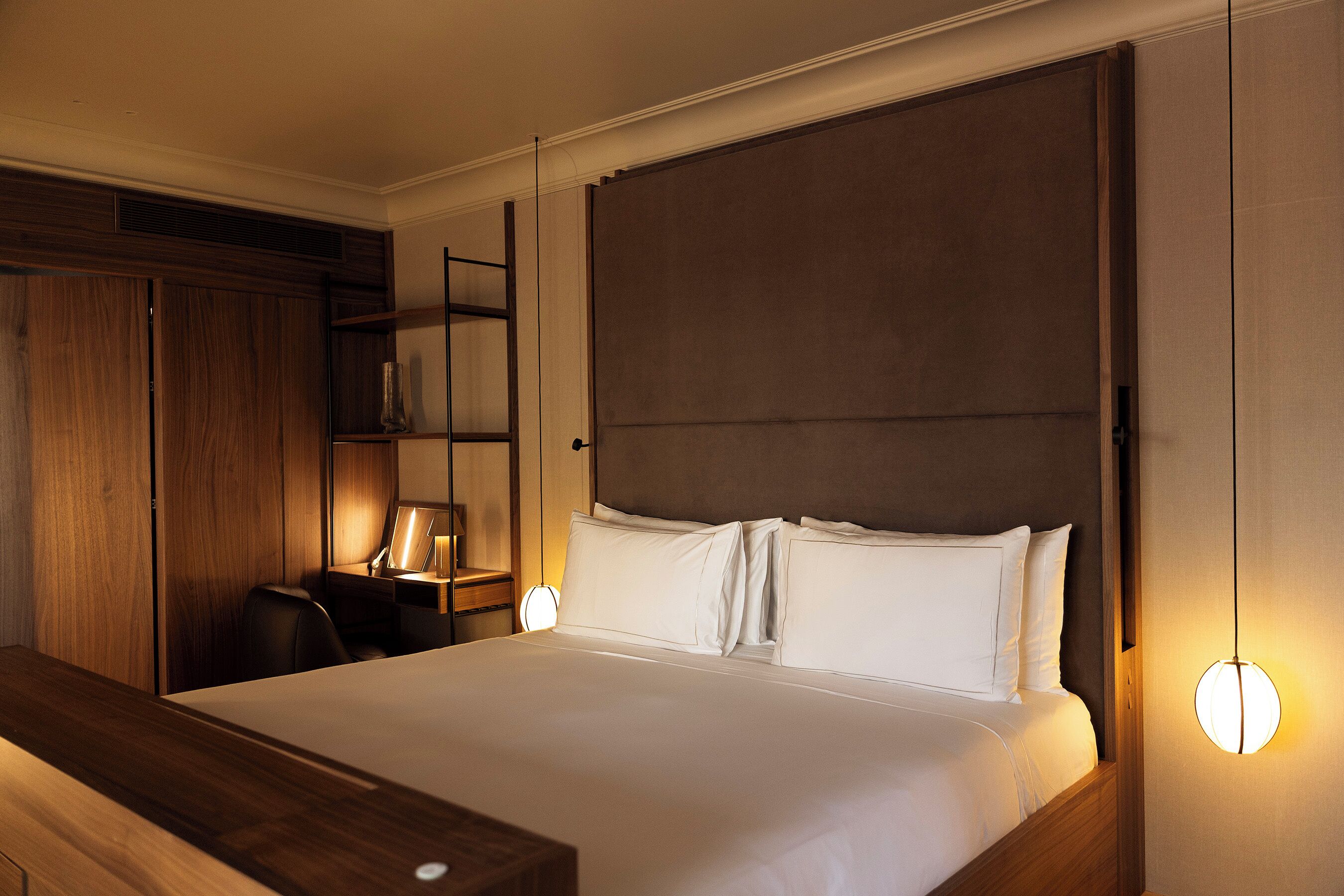 Ein Hotelzimmer mit einem großen Bett, Nachttischen, einem Schreibtisch und einem Kleiderschrank.