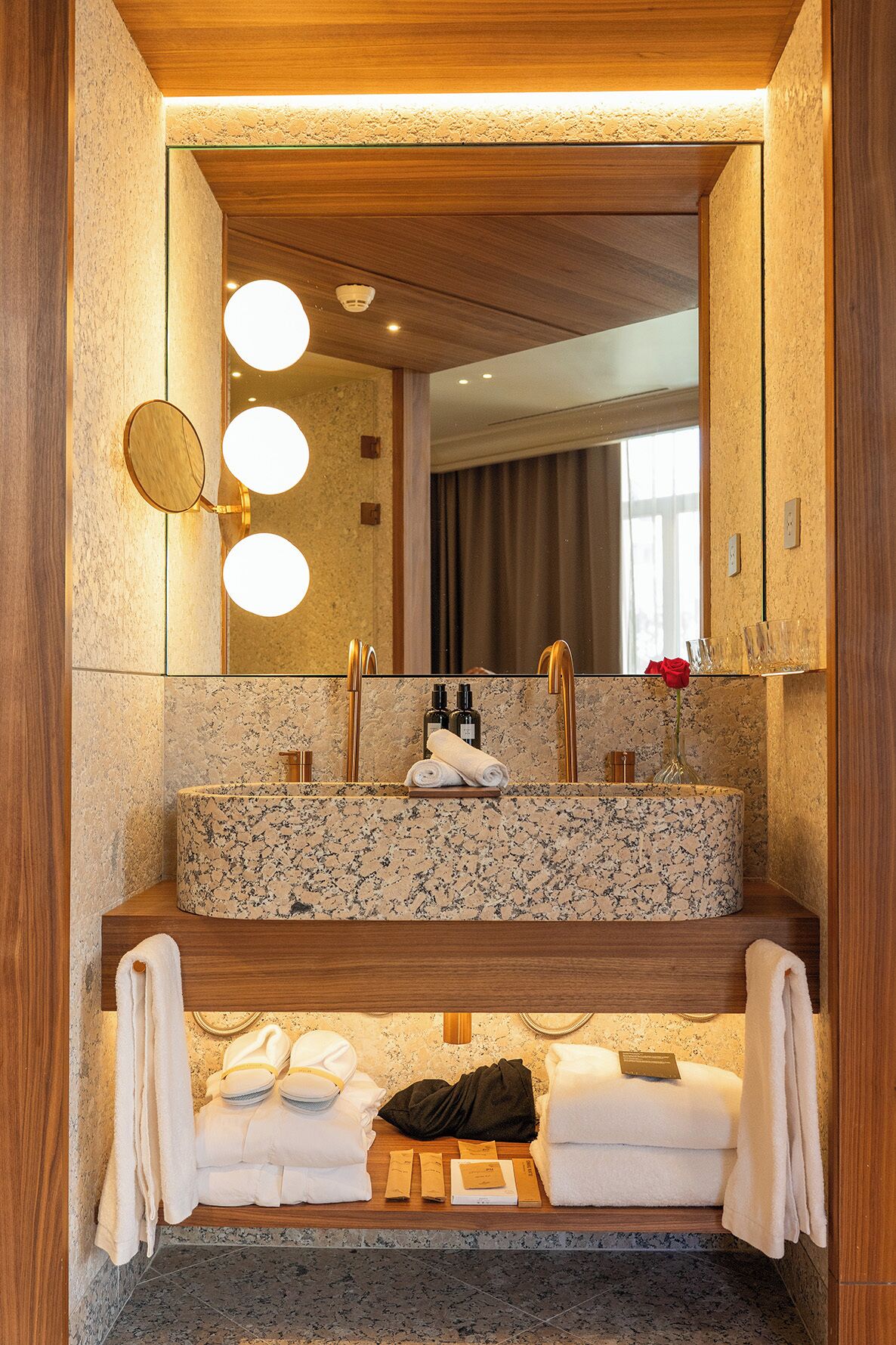 Ein Badezimmer mit einem Granittisch, einem großen Spiegel und einer Holzeinrichtung.