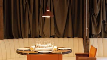 A dining area with a round table set for four, a sofa, and a wooden side table.