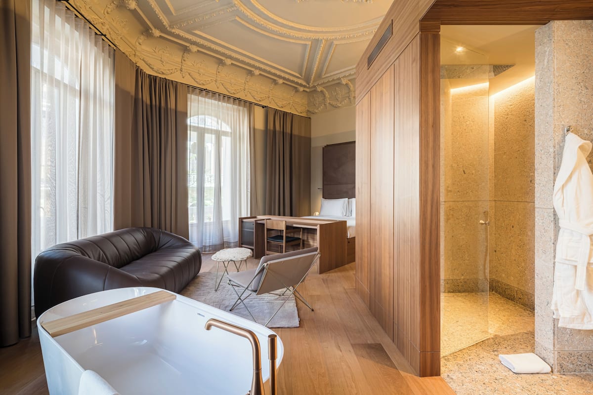 Een moderne hotelkamer met een leren bank, een kleine tafel, een stoel, een bureau en een douche.