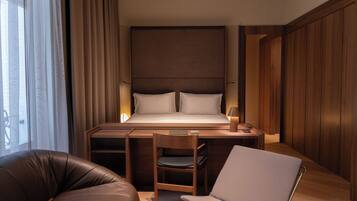 A modern hotel room with a large bed, a desk, a chair, and a laptop.