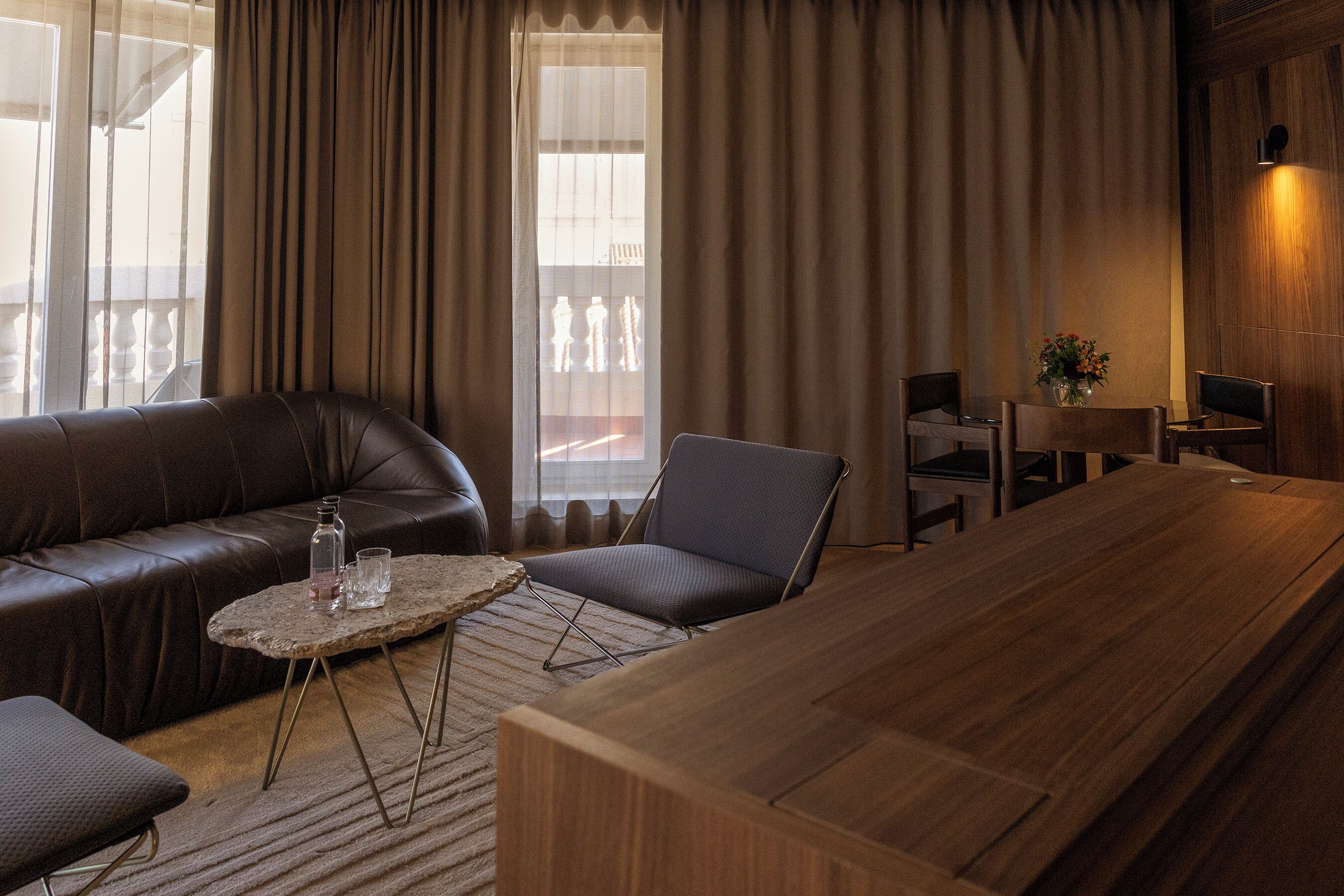 Una sala moderna con un sofá de cuero, una mesa de centro de madera y una mesa de comedor con sillas.