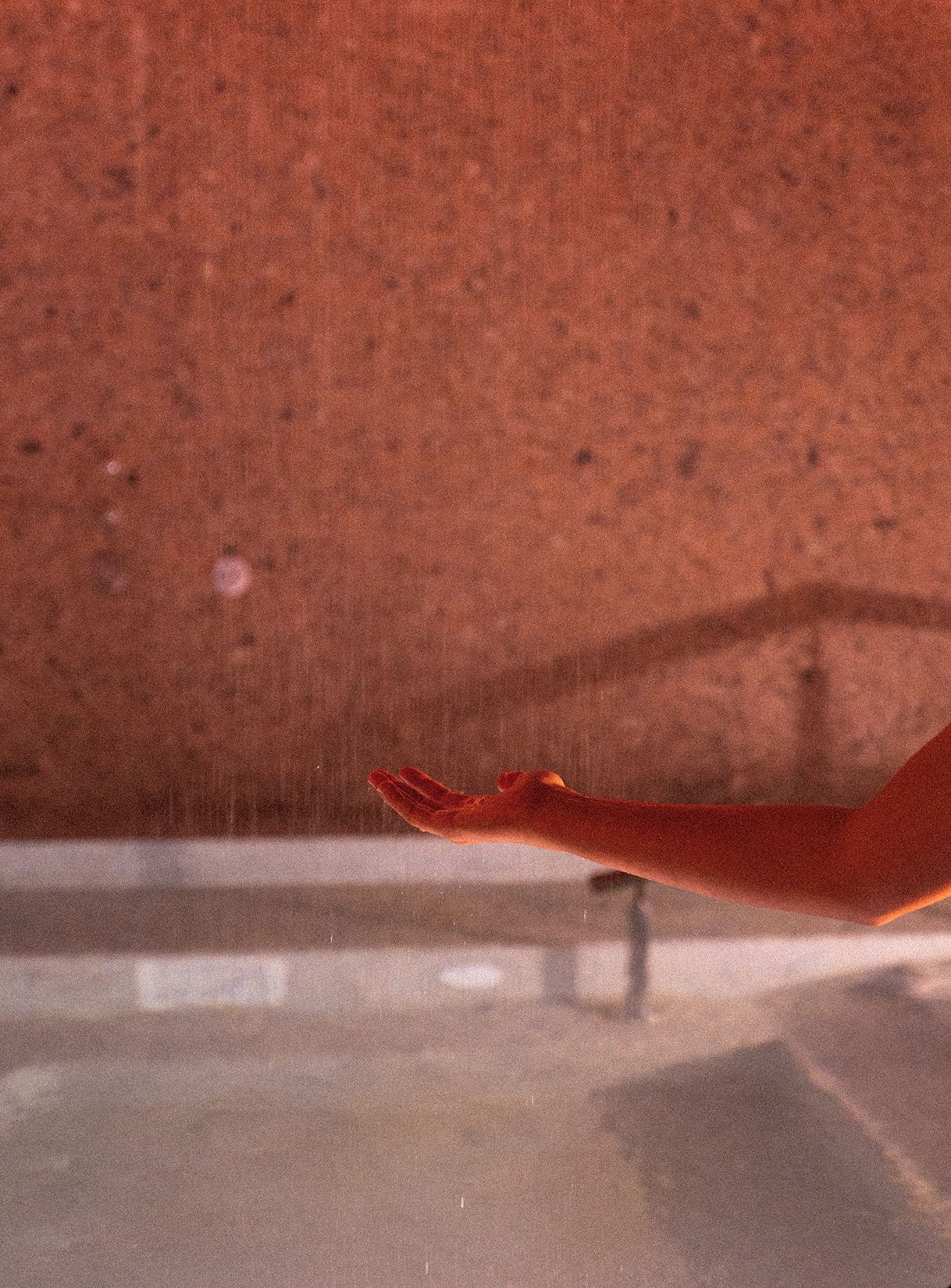 A hand reaching out, possibly in a gesture of offering or receiving, against a textured background.
