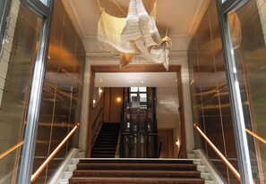 A grand staircase with a modern chandelier, leading to a second-floor landing. - Mercer Madrid  (Madrid)