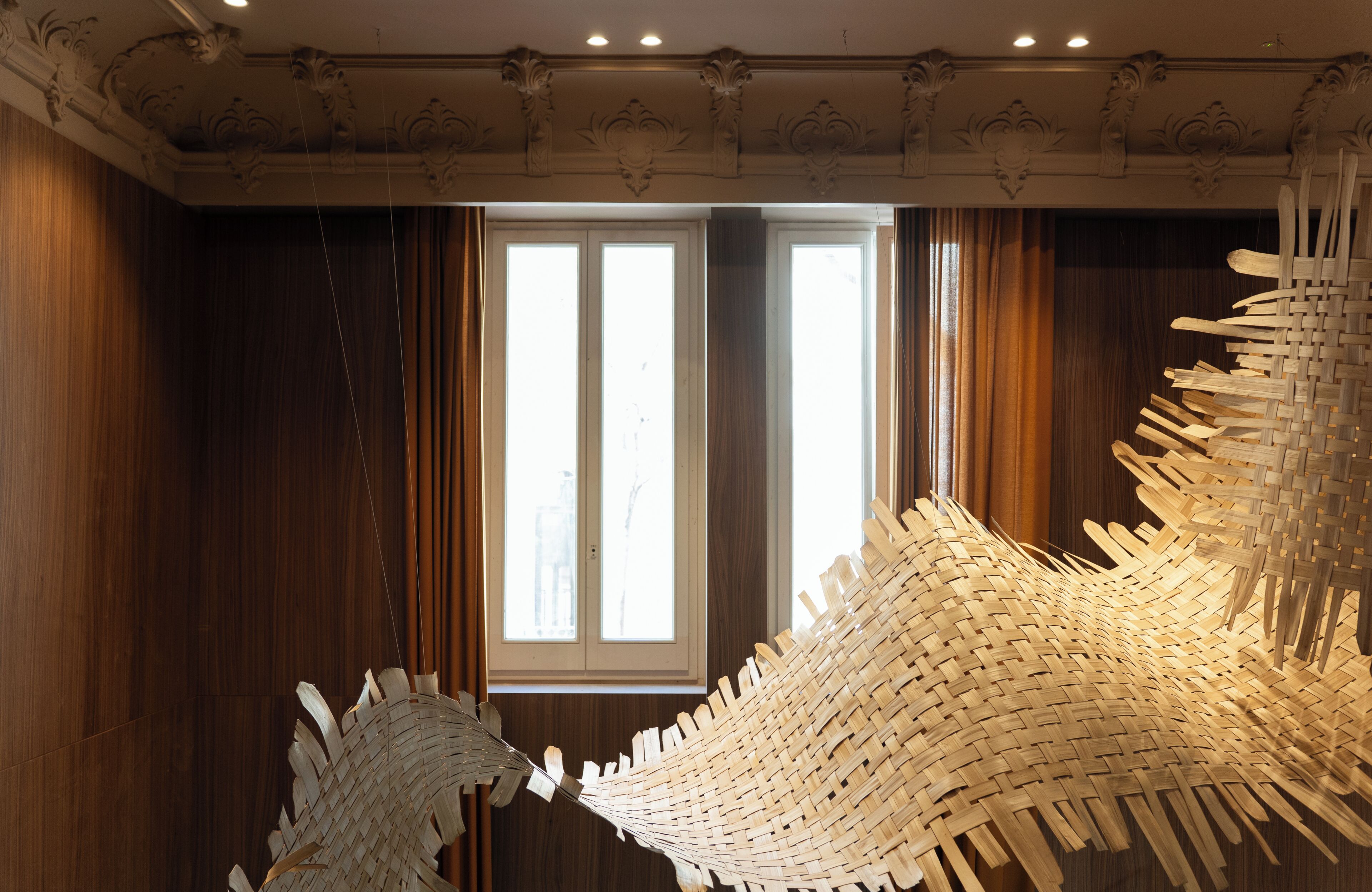 A room with wooden paneling, a large window, and a unique woven light fixture.