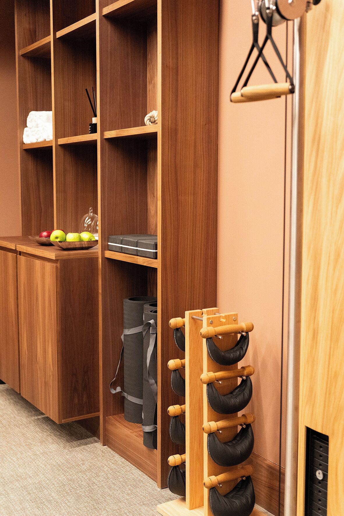 A wooden storage unit with shelves, a shoe rack, and a small table with apples and a tissue box.