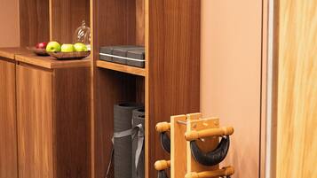 A wooden storage unit with shelves, a shoe rack, and a small table with apples and a tissue box.