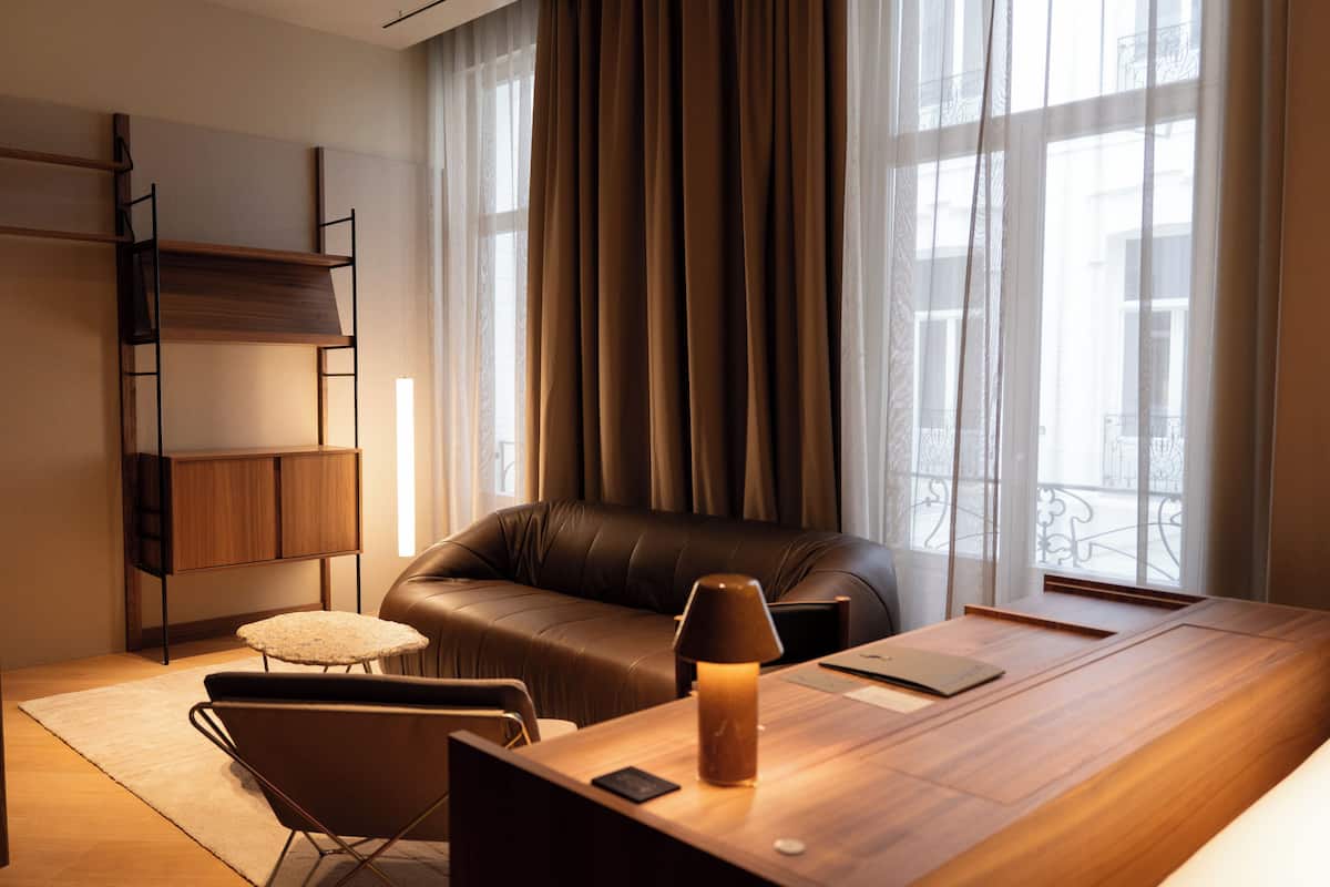 Een moderne woonkamer met een leren bank, een houten salontafel, een lamp en een boekenkast.