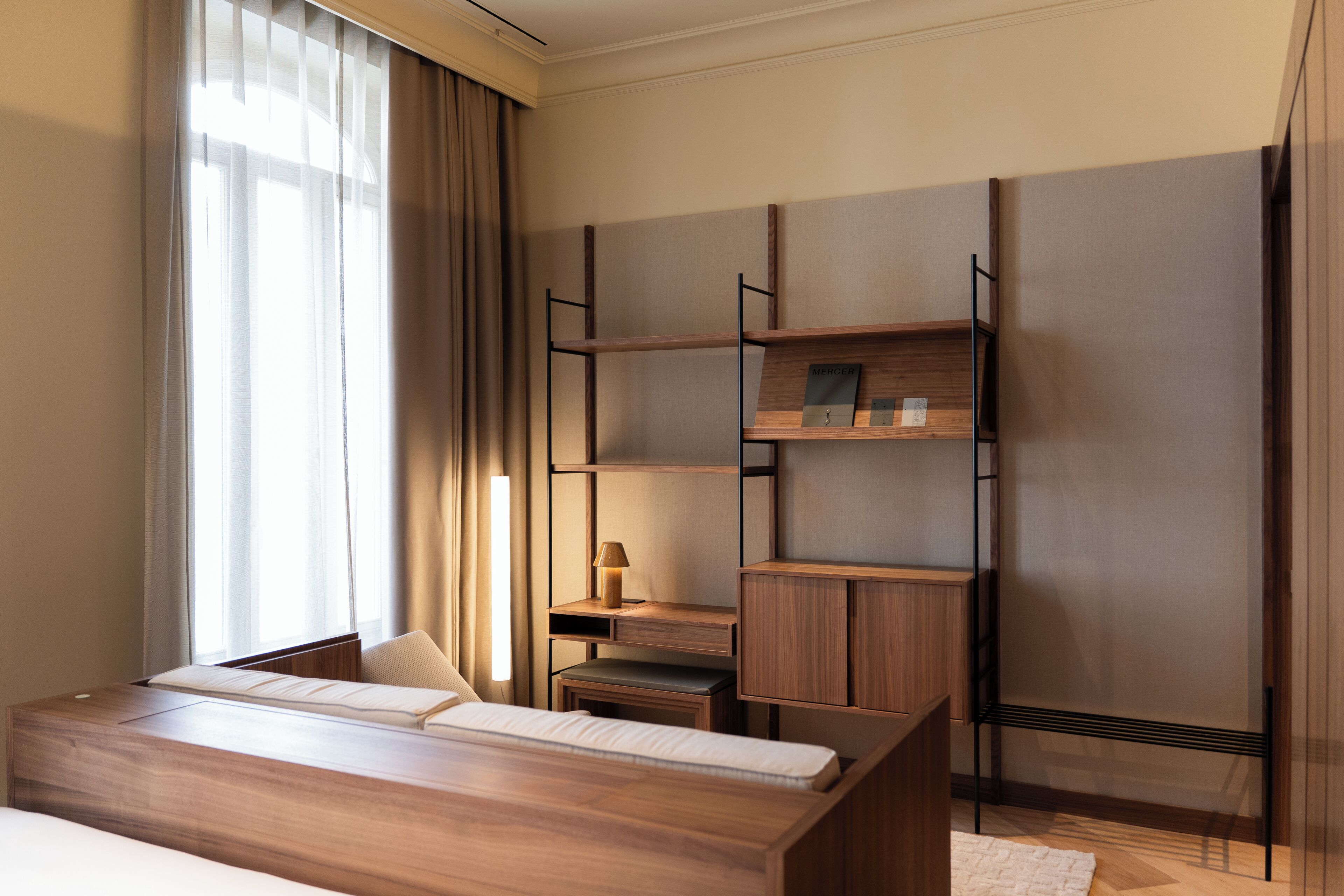 Una habitación de hotel moderna con una cama de madera, un escritorio y estanterías empotradas.