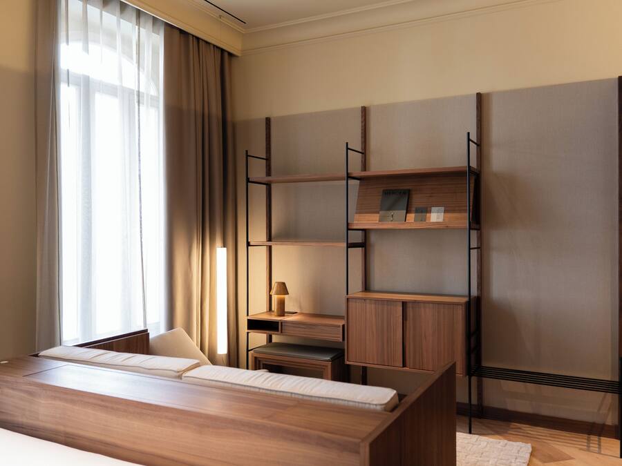 Una habitación de hotel moderna con una cama de madera, un escritorio y estanterías empotradas.