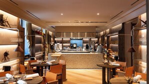Een modern restaurantinterieur met een centrale bar, houten tafels en stoelen.