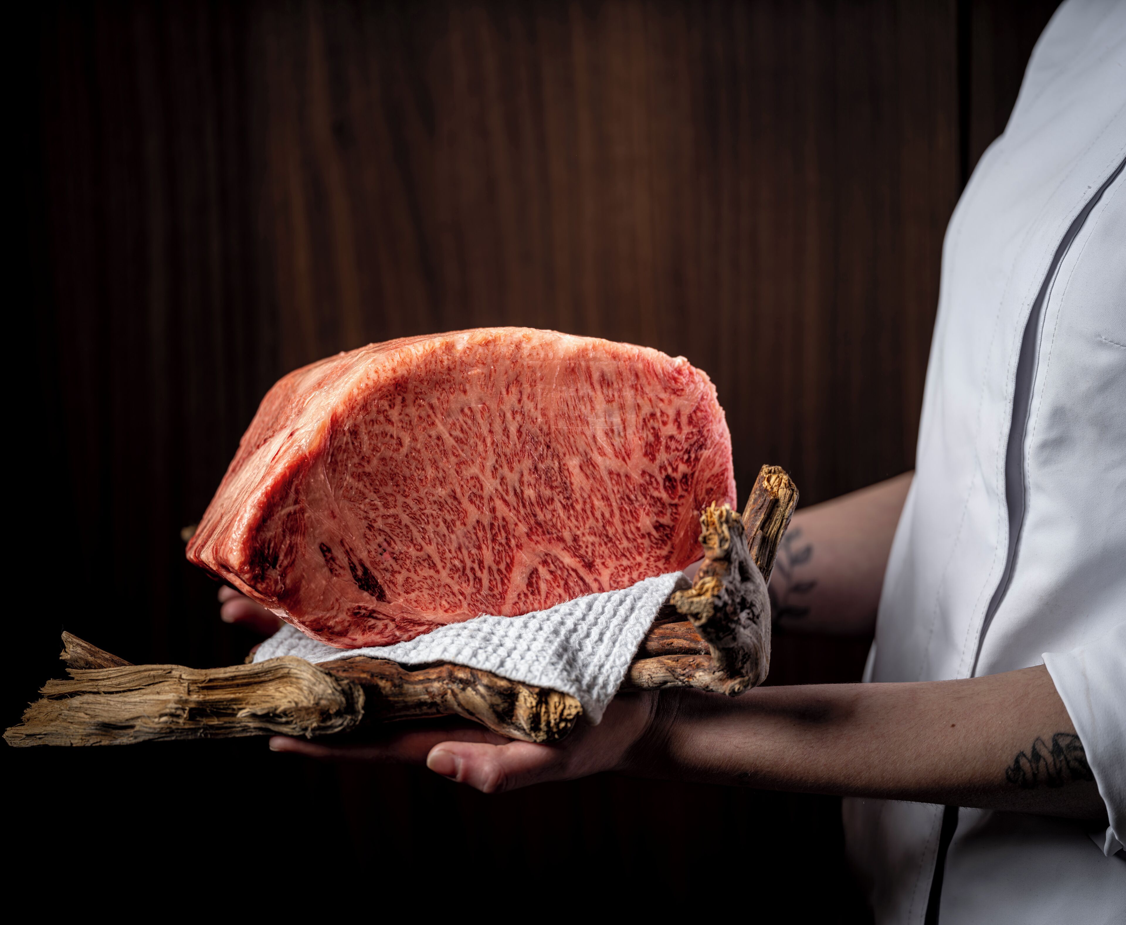 Una persona che tiene in mano un grande pezzo di carne e un oggetto di legno.