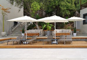 A poolside area with lounge chairs and white umbrellas, surrounded by greenery and a stone staircase. - One bedroom apartment in tranquil Bodrum with balcony (BODRUM)
