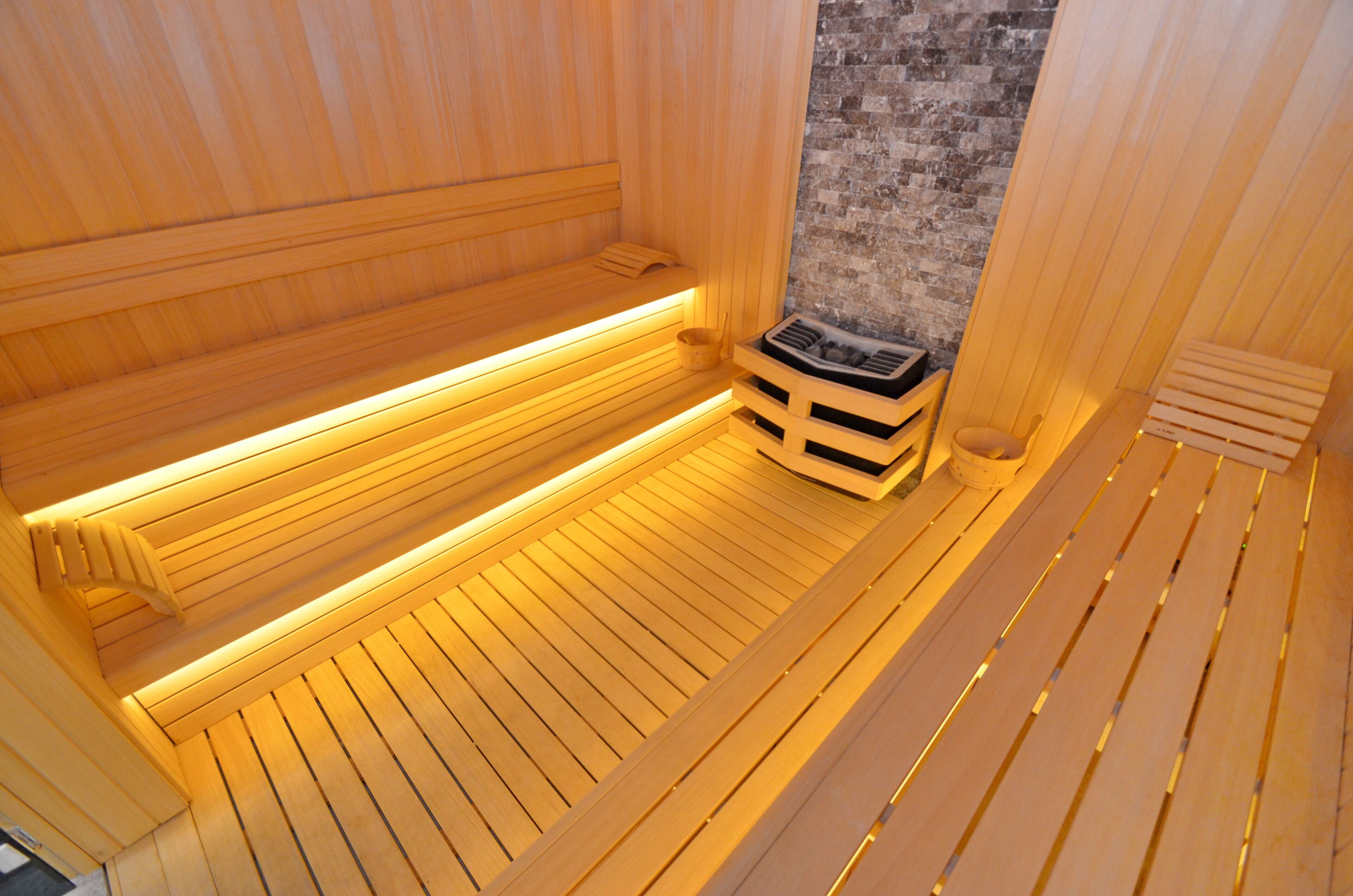 Una sauna in legno con panche e una seduta.