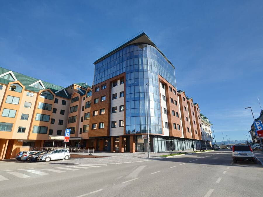 Un immeuble moderne à plusieurs étages, doté d’une façade en verre et d’un parking situé à l’avant.