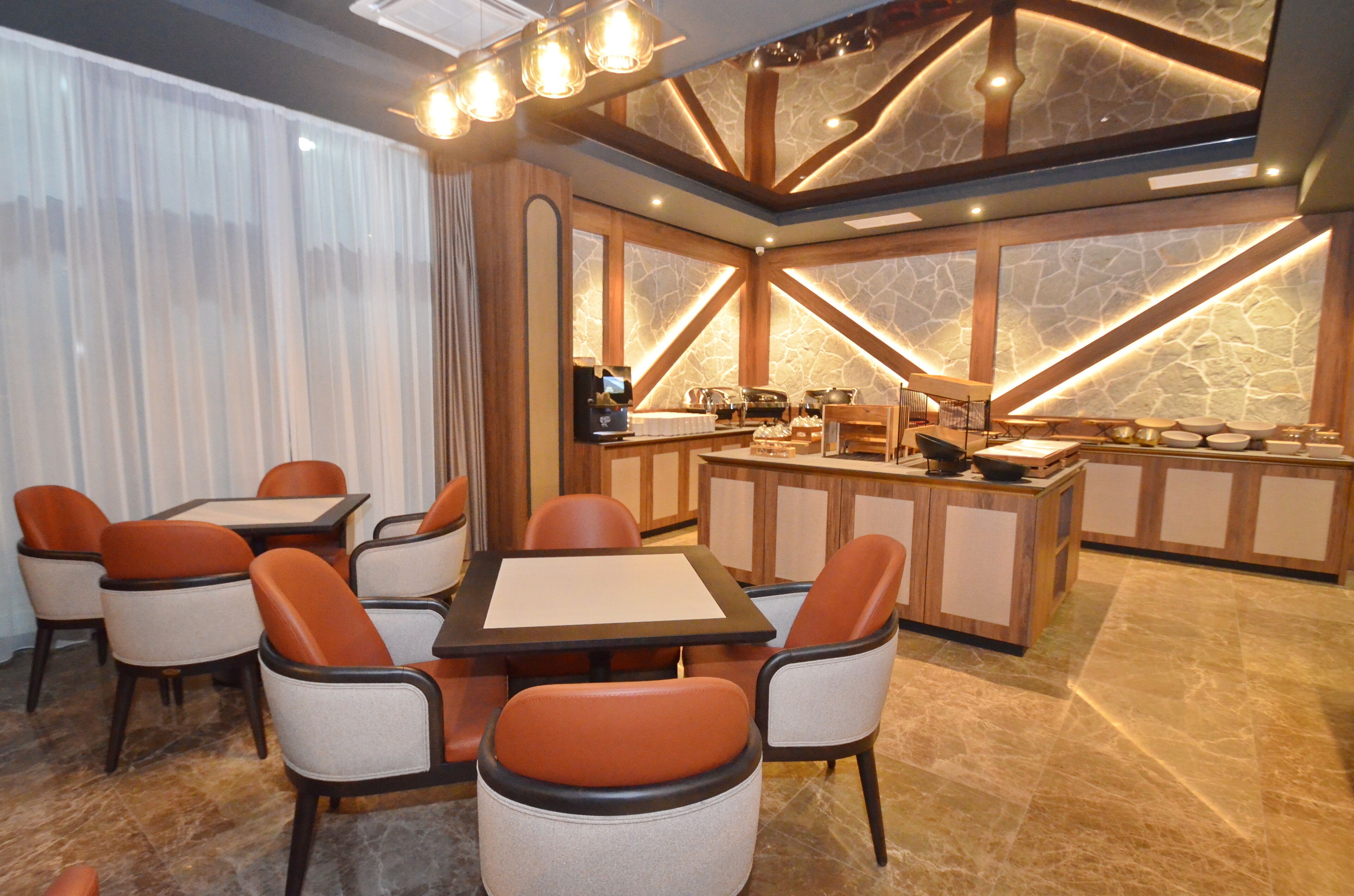 A dining area with a central table and chairs, a kitchen in the background, and a stone accent wall.