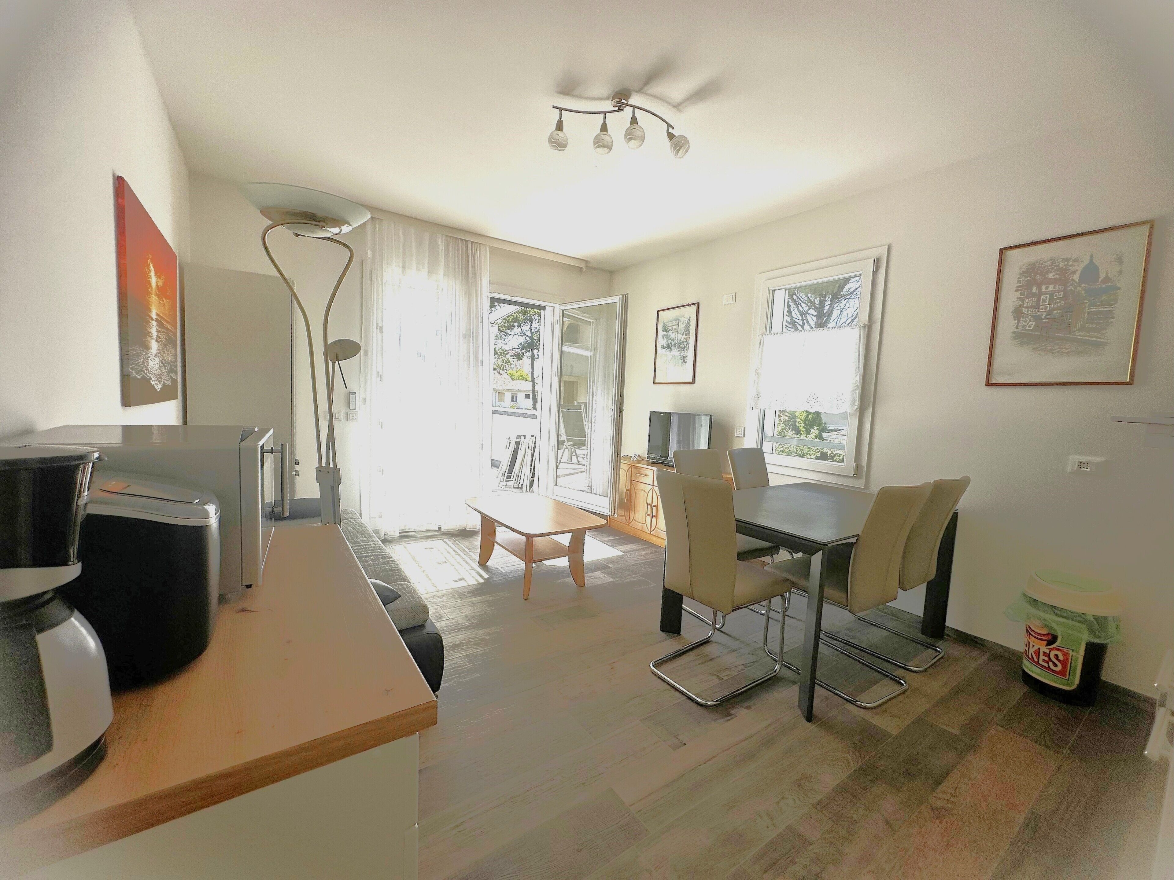 A modern living room with a dining area, a sofa, a coffee machine, and a television.