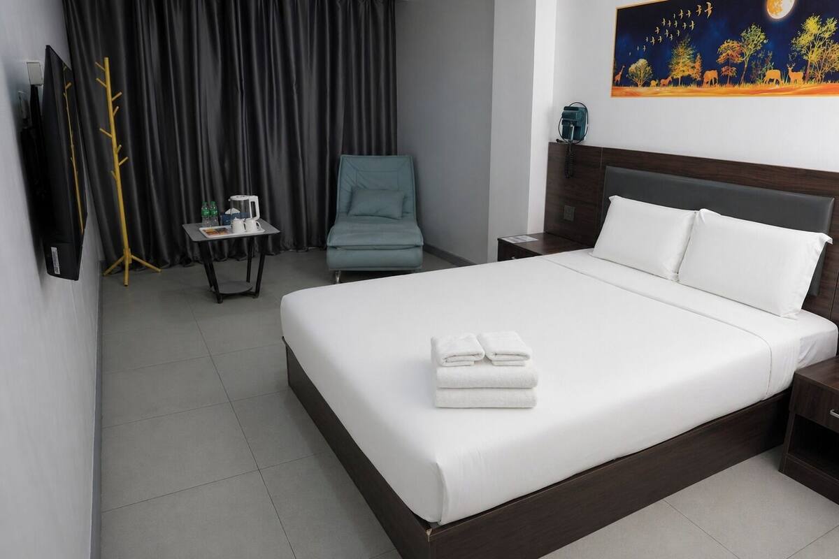 Une chambre d’hôtel avec un grand lit, un bureau avec une chaise, une télévision et un tableau au mur.