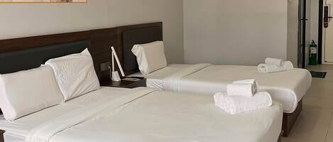 A hotel room with two beds, a painting on the wall, and a door leading to another room.