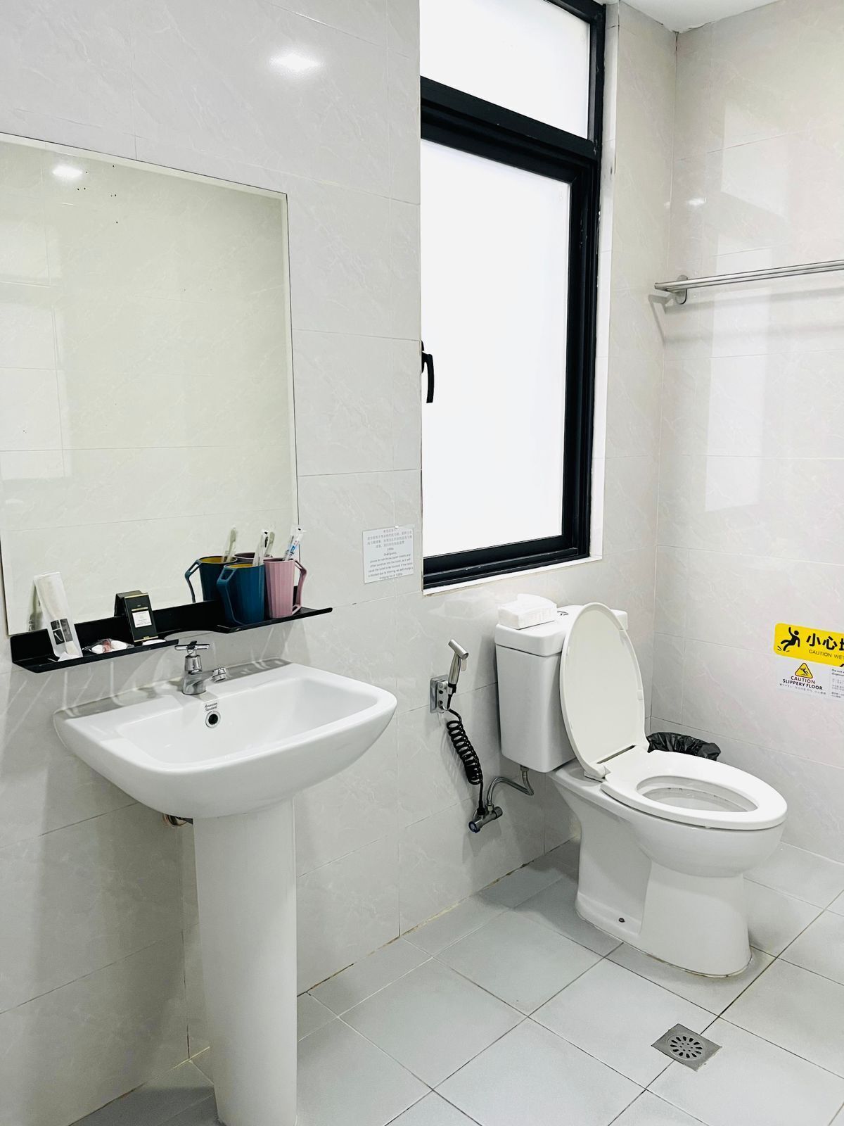 A bathroom with a white sink, toilet, and a window.