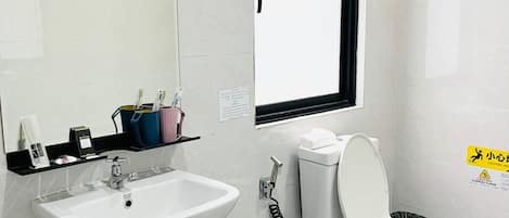 A bathroom with a white sink, toilet, and a window.